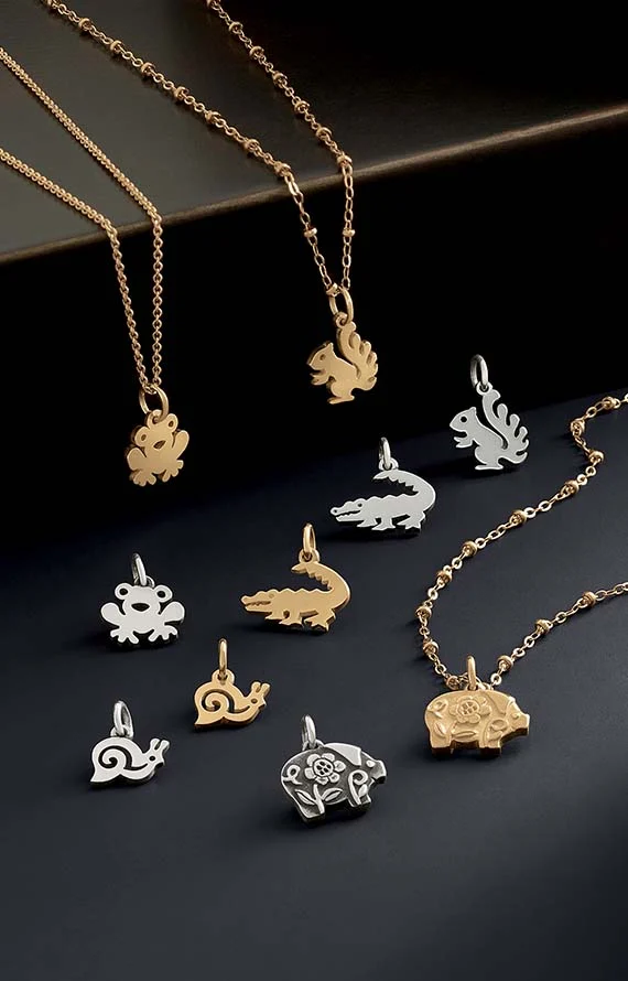 Animal-themed charms in sterling silver and 14K gold on a black background