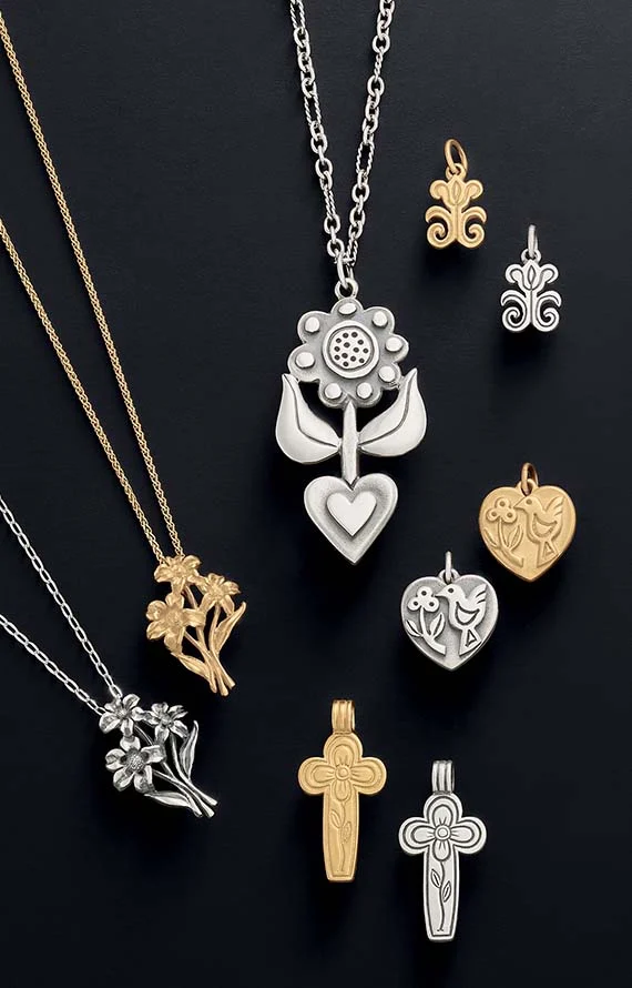 Flower-, heart-, and cross-themed charms in sterling silver and 14K gold on a black background